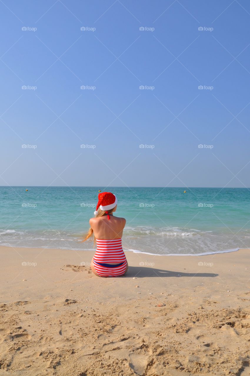 Woman in red santa hat celebrating Christmas on kite beach during winter trip to Dubai