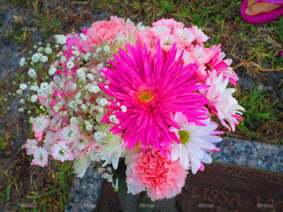A closeup of a vivid bouquet of pink and white flowers at a gravesite