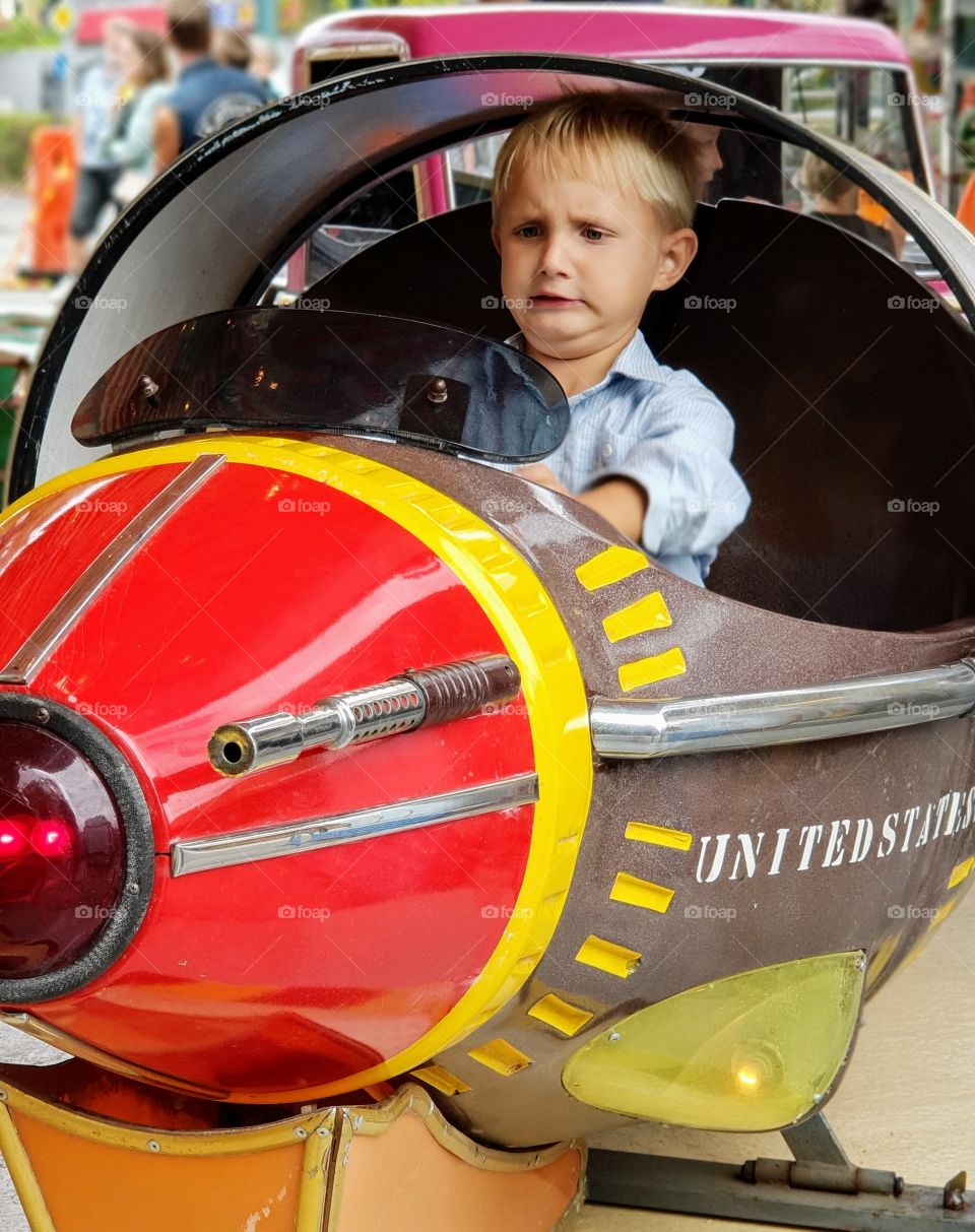 A consentraded boy riding a plane in an amusement park