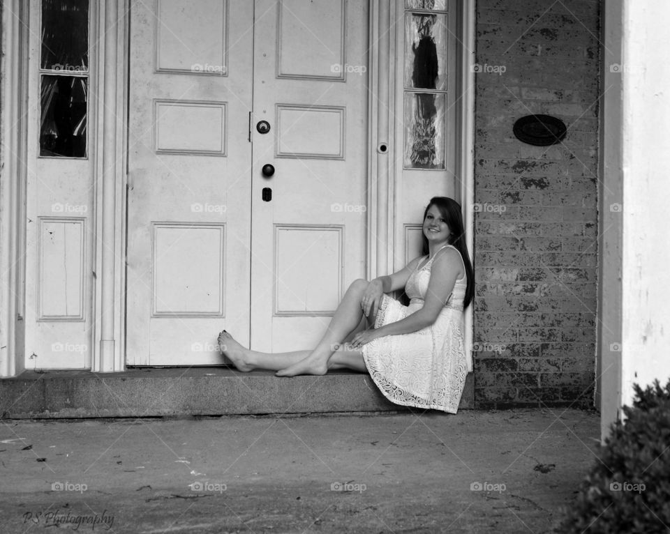 Young woman sitting near closed wooden door