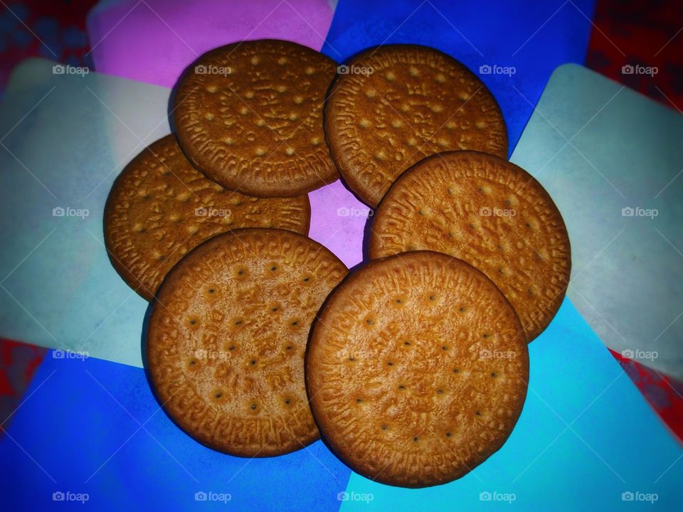 Delicious cookies arranged in circle against a colourful background