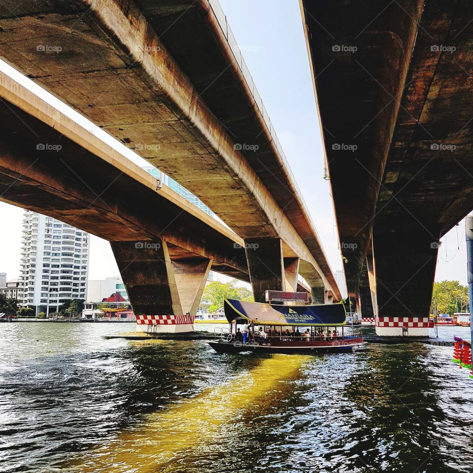 Boat floating on river under bridge