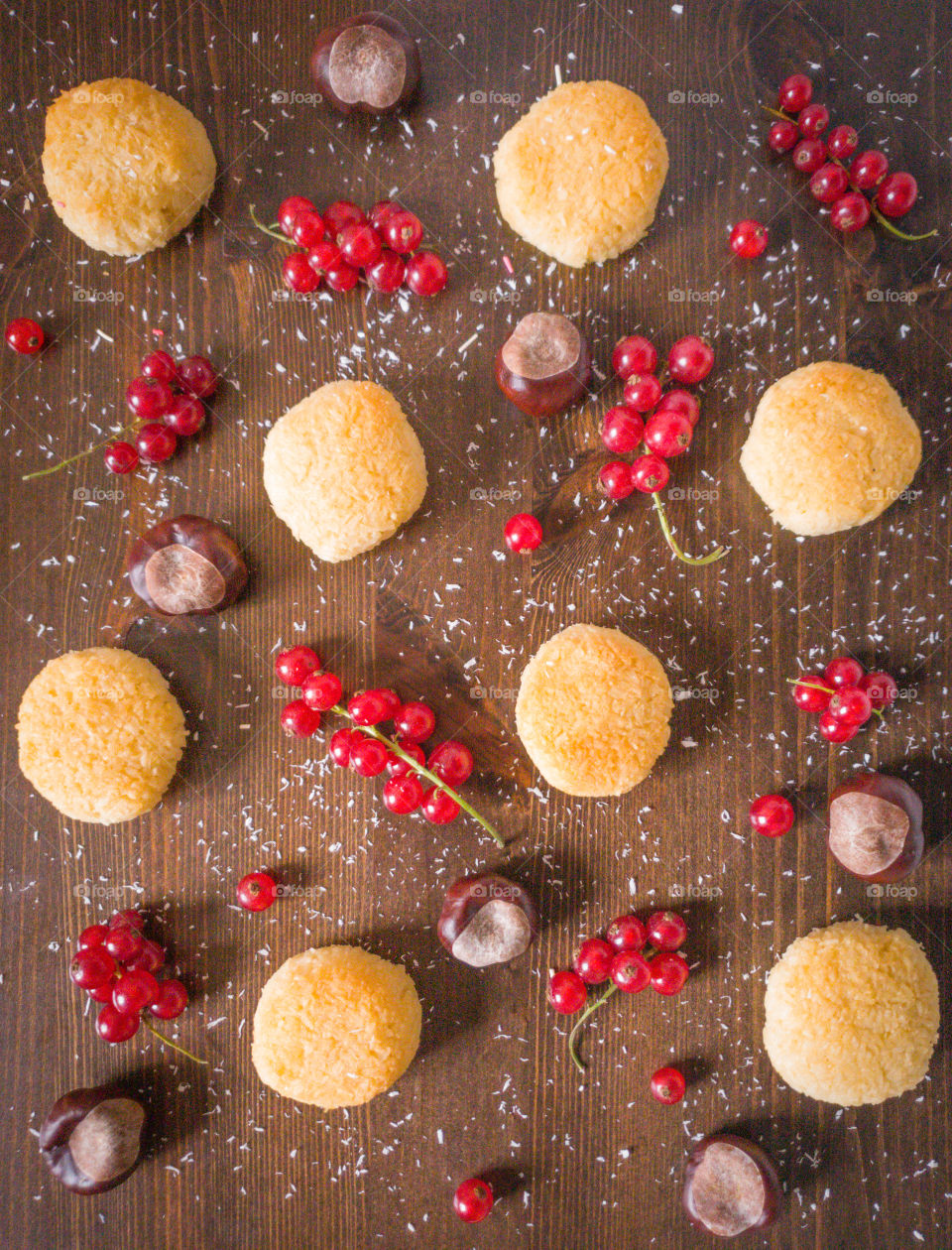 Food photography, top view.  Coconut cookies with sprigs of red currant and peeled chestnuts sprinkled with coconut flakes on a wooden dark brown background.  Autumn composition