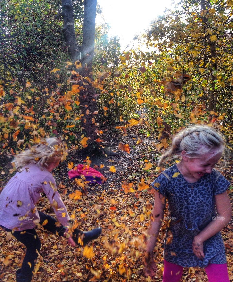 Small kids playing with autumn leaves