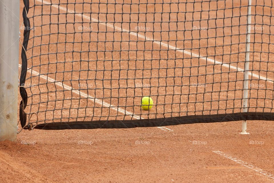 Clay tennis court, net and tennis ball