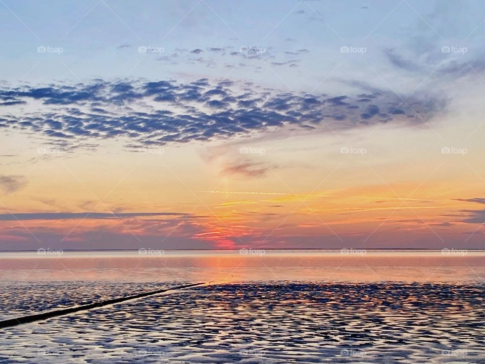 Beautiful sunset at the Waddenzee, Holland, Netherlands, sky and water in orange blue and yellow
