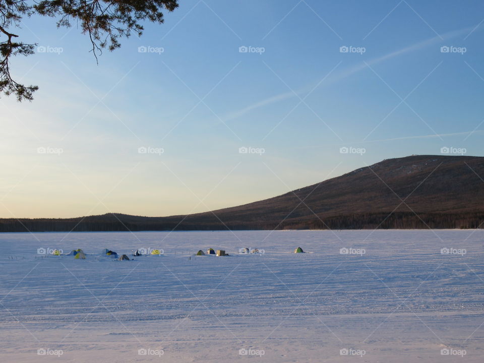 tents of fishermen on the ice in the pond in the Urals in Russia