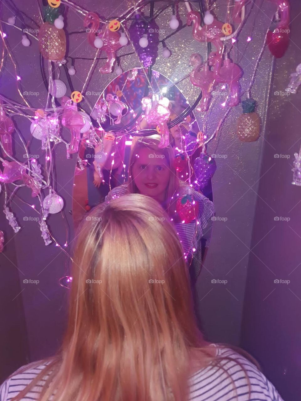 mujer rubia  reflejada en un espejo lleno de flores y luces en un bar de buenos aires argentina.