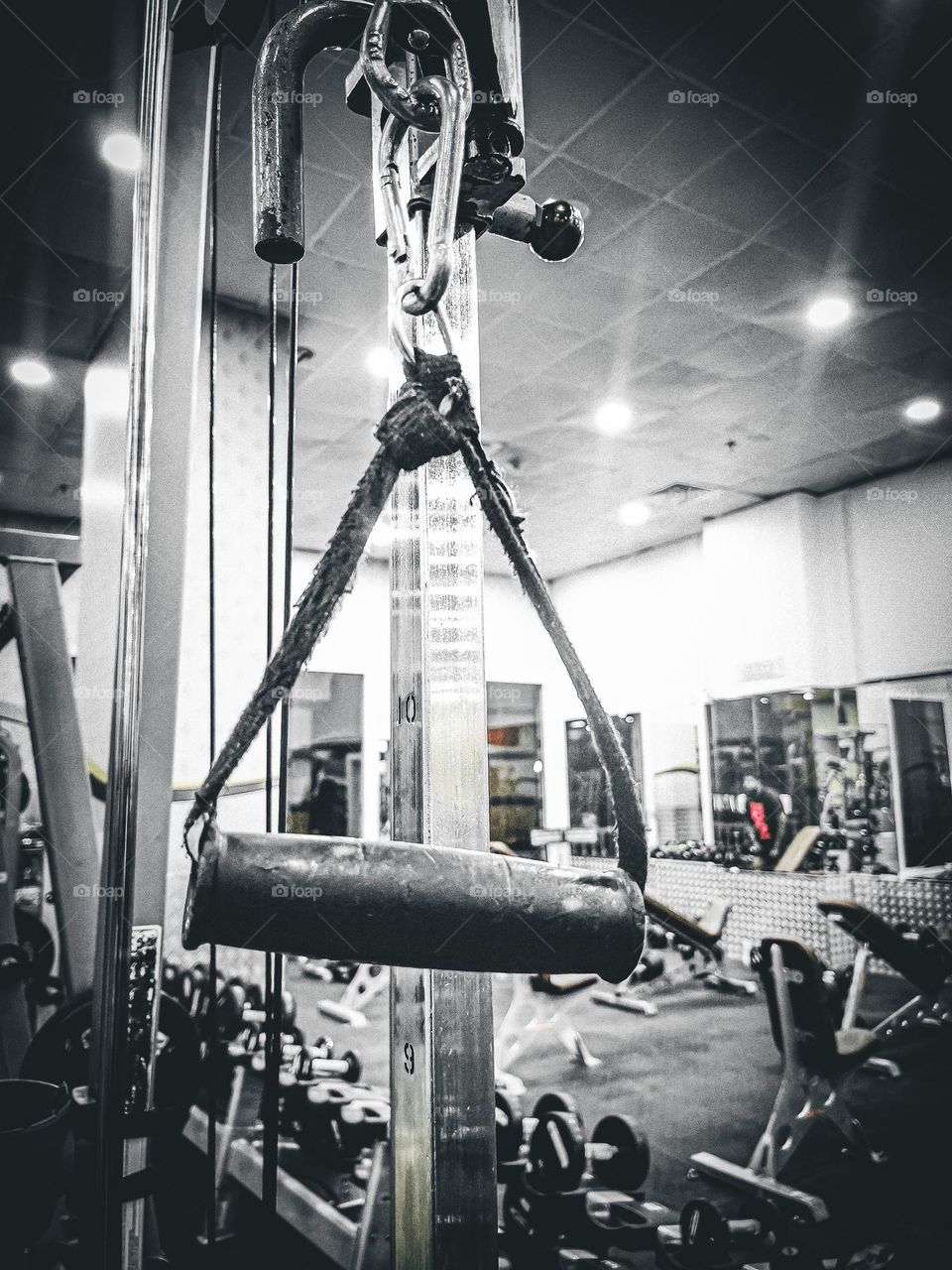 Pull handle at a gym, with equipment and dumbbells in the background. 