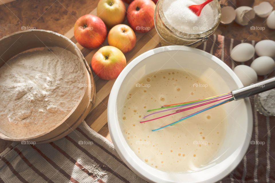Making an apple pie dough using eggs, flour, sugar and apples.