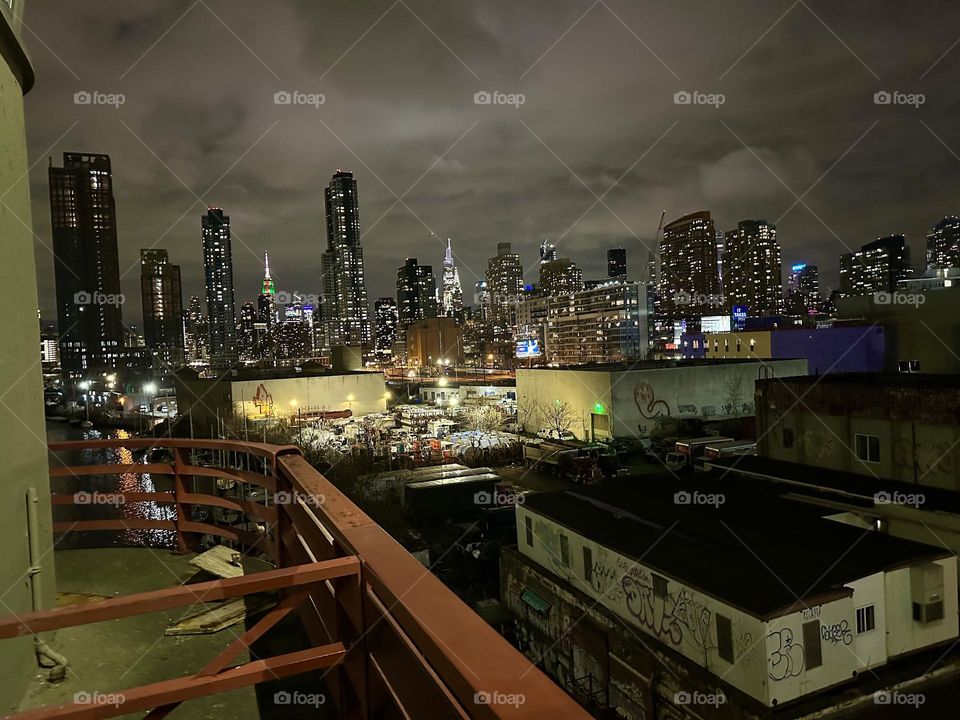 This is “Newtown Creek” at night seen from the “Pulaski Bridge” that connects “Greenpoint”, Brooklyn to LIC, Queens. In the distance we see “Manhattan” including the “Empire State Building” and the “Kreisler Building”. 2023. Hypnotic Productions