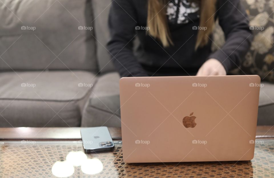 Woman typing on Rose Gold MacBook Air with Midnight iPhone 12 Pro Max