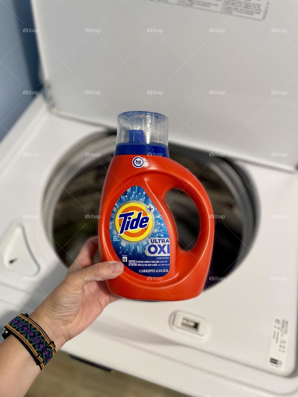 Woman holds Tide bottle of detergent, doing laundry with Tide Detergent, washing clothes with Tide 