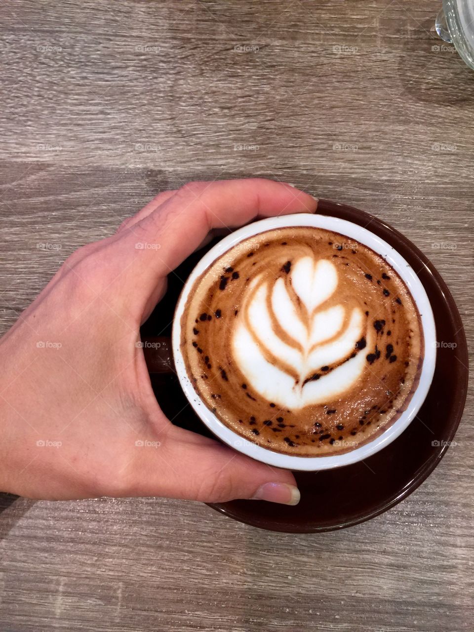 Human's hand holding coffee cup on table