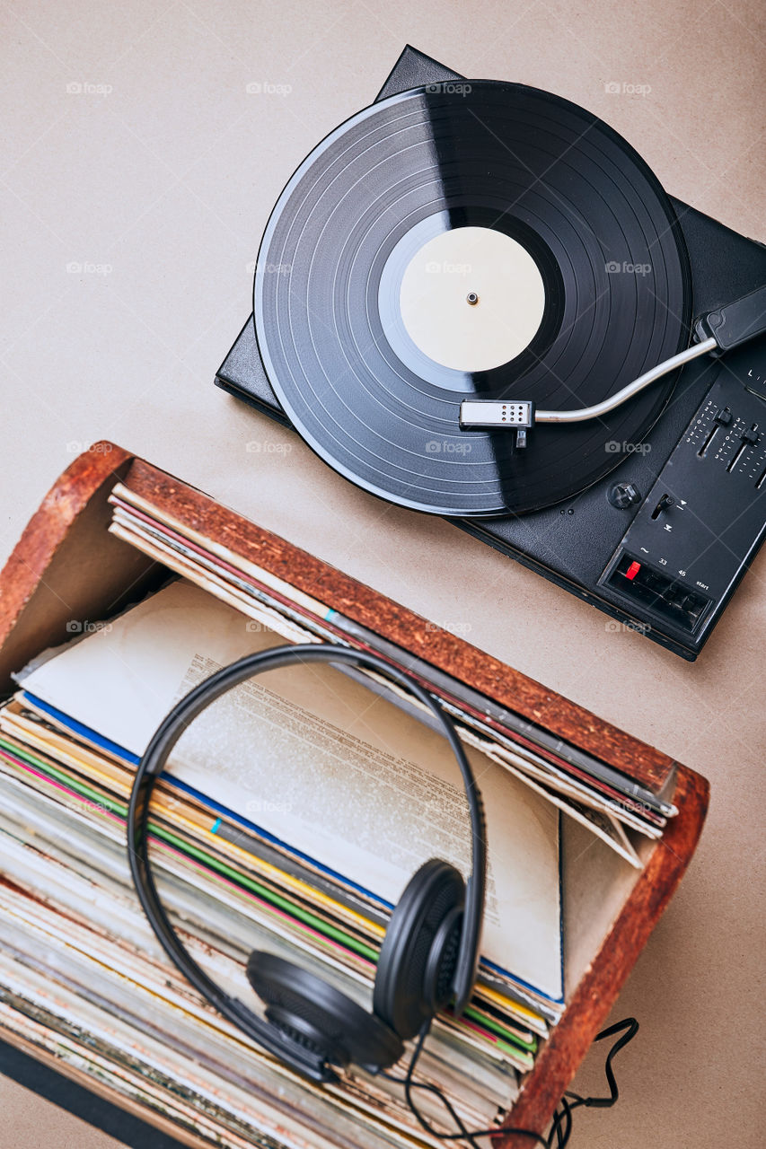 Stack of black vinyl records, turntable vinyl player and headphones. Classic stereo set. Candid people, real moments, authentic situations