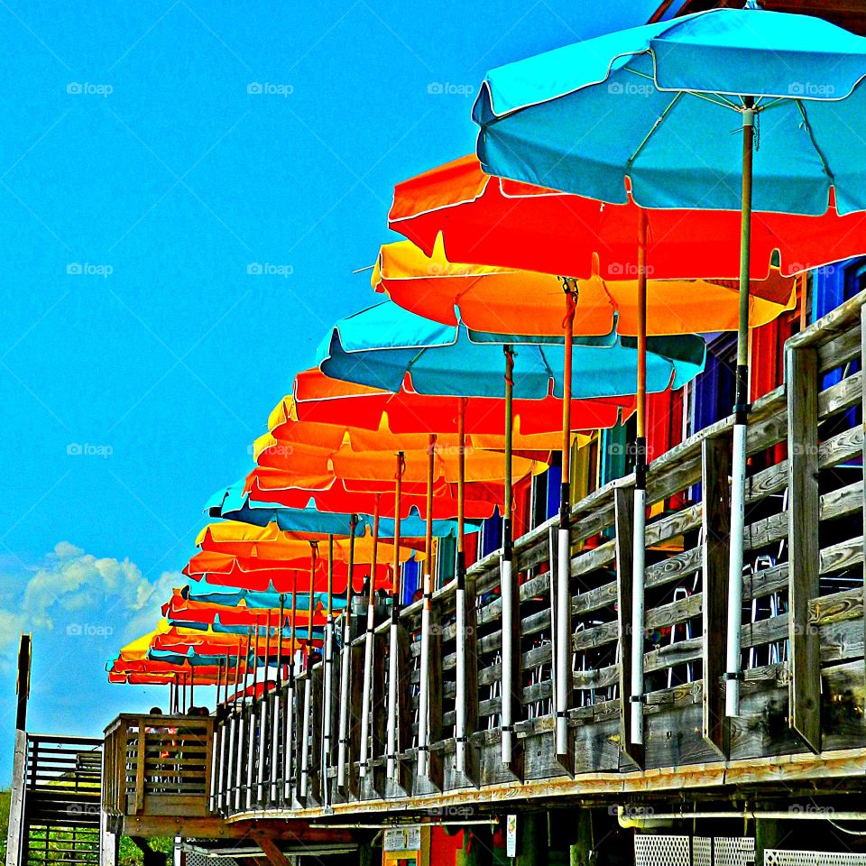 Multiverse - Multiple multicolored umbrellas line the the patio for outdoor dining 
 to protect dinners from the sweltering sun off the Gulf of Mexico. 