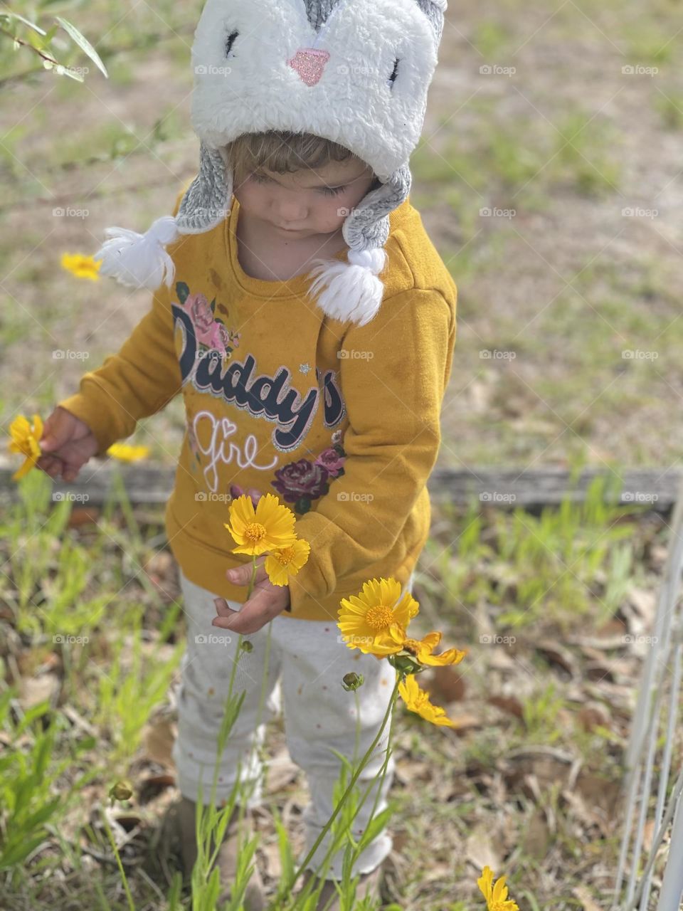 Toddler fascinated & captivated by the beautiful wild flower plants growing in her yard. 