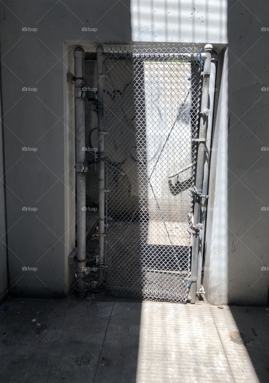 A gate located beneath an overpass and Bart track line in Oakland California.