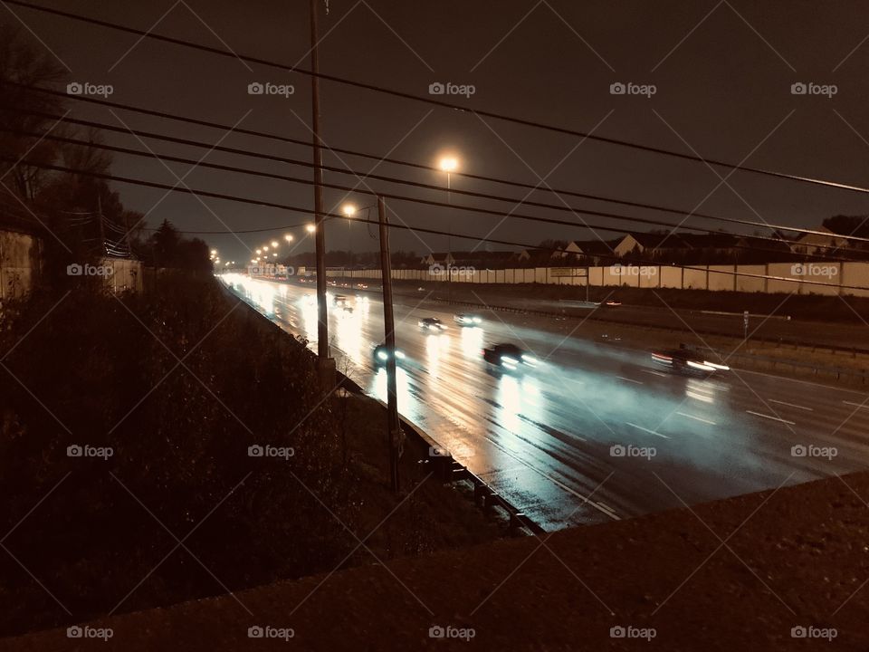 After dark, in the Midwest. A look down onto the Highway, from a city bridge. It’s raining.