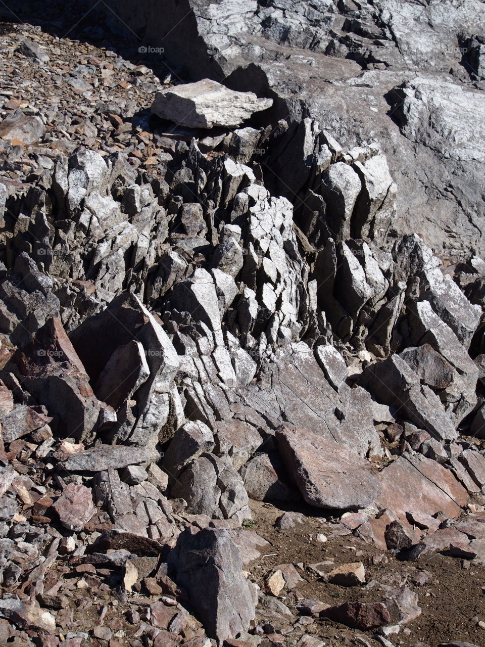 Jagged rocks and boulders along the shoreline of Ochoco Lake in Central Oregon on a sunny spring day.