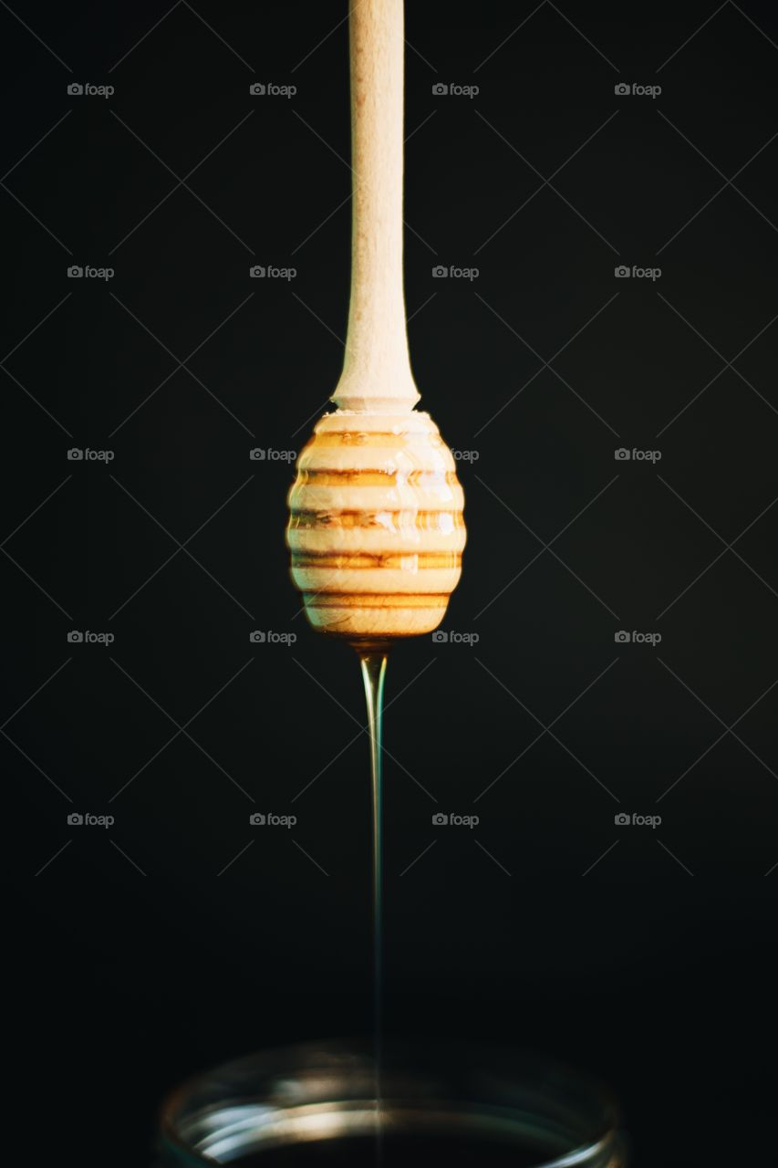 Honey and honey spoon on a light background. Sweet honey in the jar, place for text.