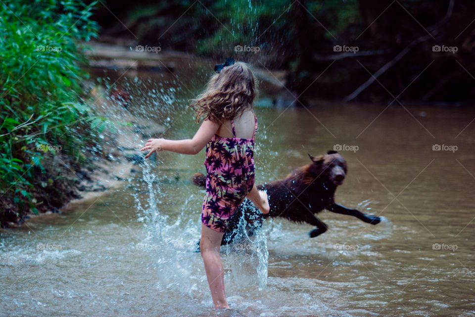 A Girl and Her Brown Dog Playing in the Creek