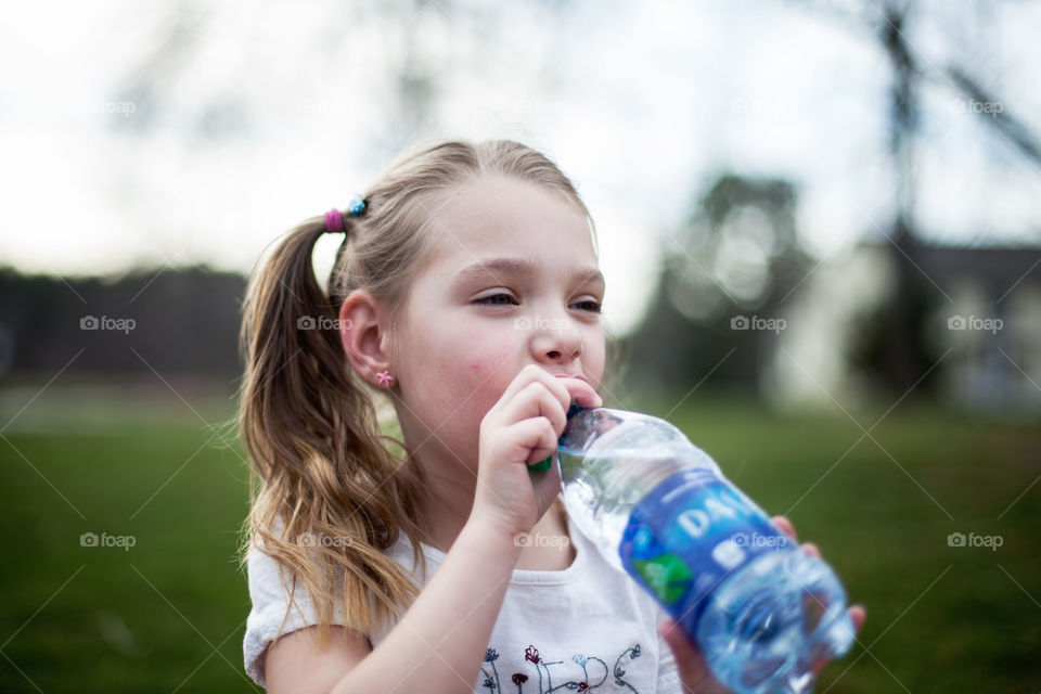 Sweet, little, pigtailed blonde drinking water. 