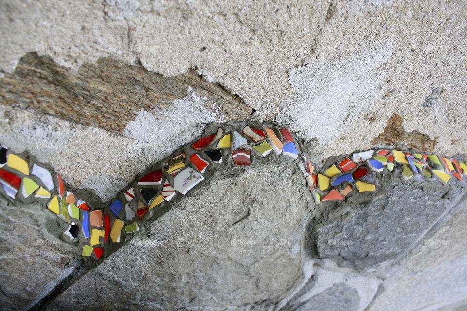 I create this wall design of old, broken, colorful cups and plates