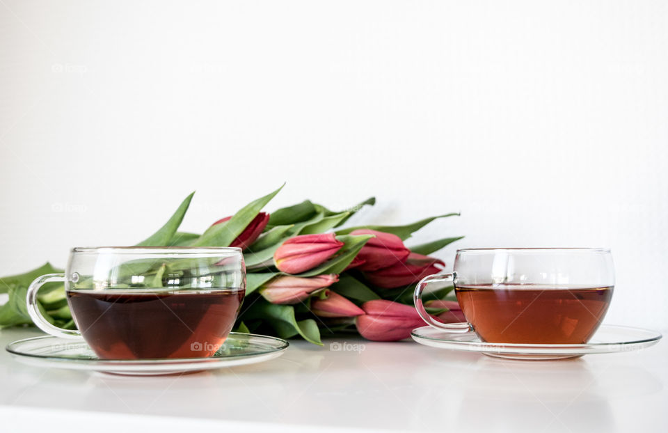 Black tea and flowers on white background