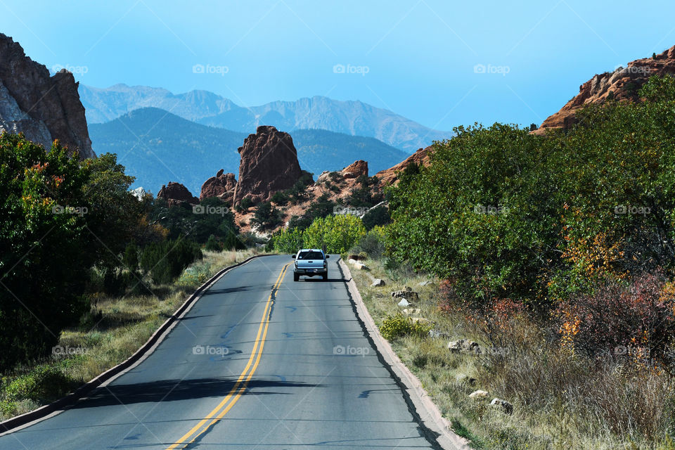 A pick up truck in the distance ahead drives down the winding country road in beautiful Garden of the Gods state park in Colorado Springs.