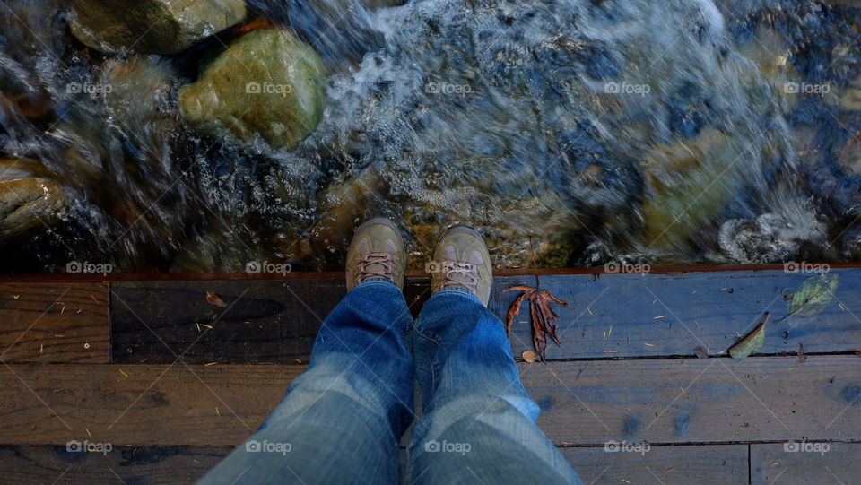 Water flowing under a wooden pedestrian bridge