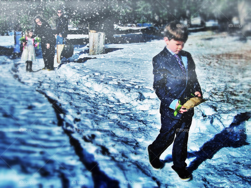 Boy in formal wear walking through snow at a wedding