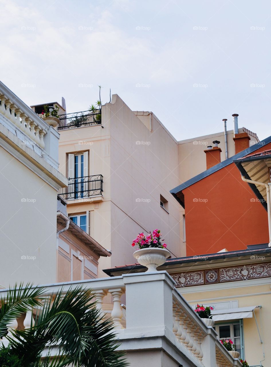 A pleasant architectural moment in the life of a small town in the south of France in light pastel beige, peach and yellow tones with a splash of pink and orange 