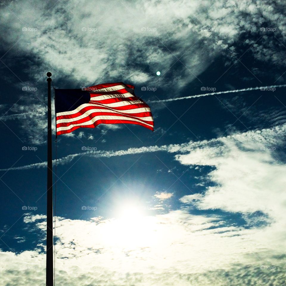 Flag flies for freedom. US flag flies freely in clouded skies unwaivering