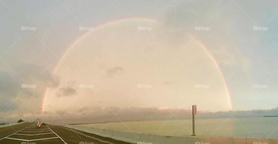 A full rainbow forms over the ocean after a storm