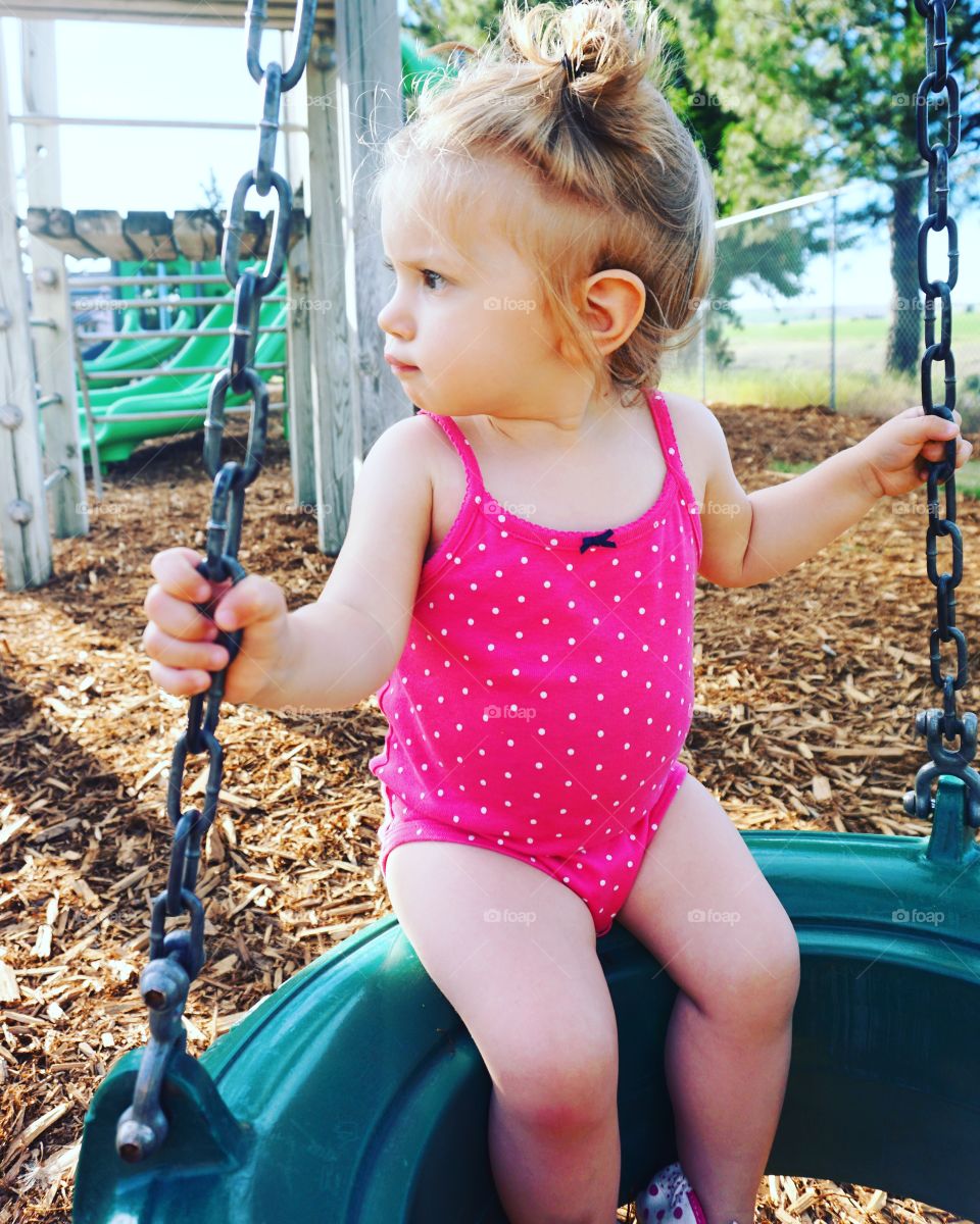 Cute little girl sitting on swing