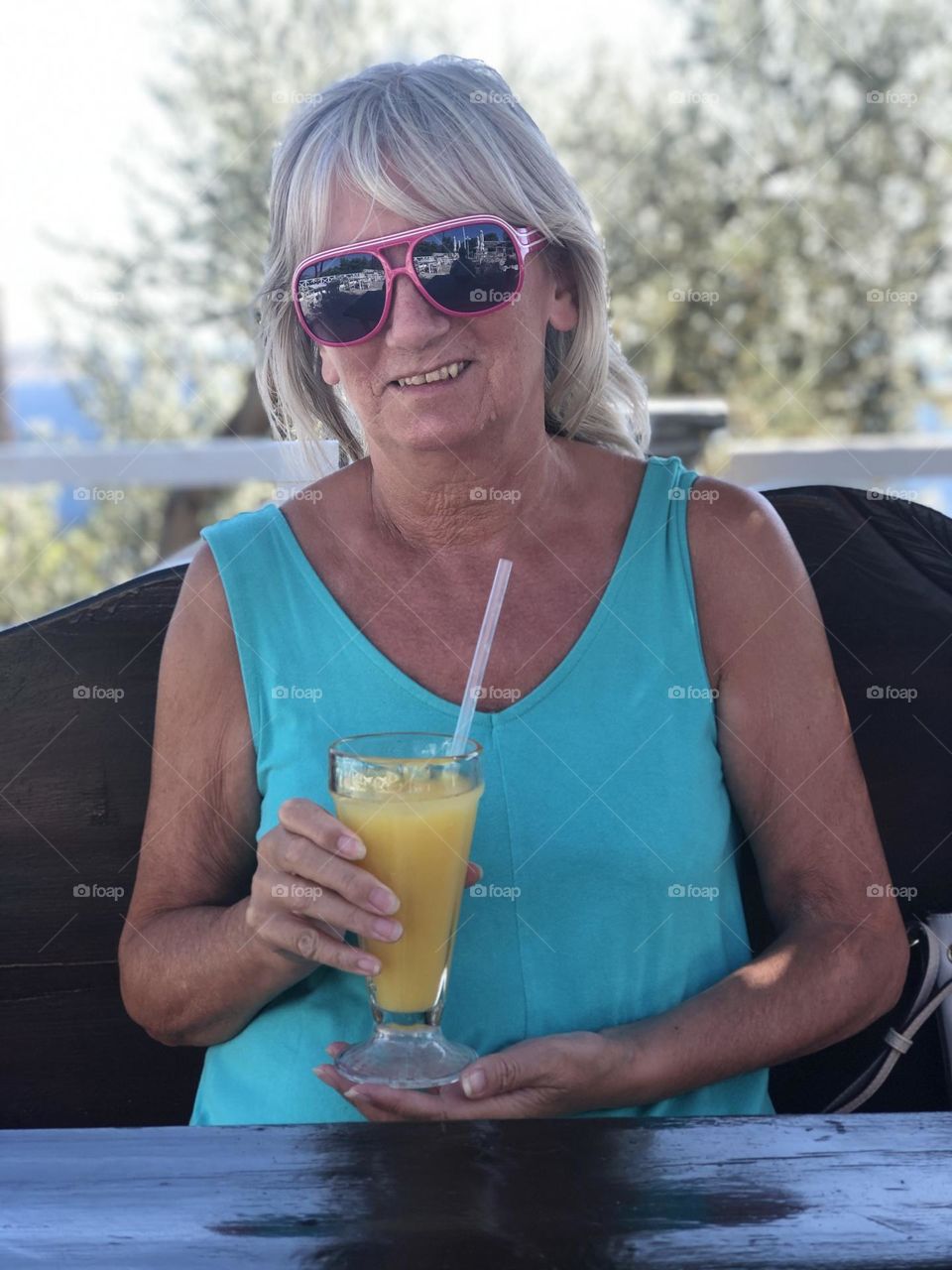 Female wearing sunglasses, holding a glass of fresh orange juice, drink, smiling, happy