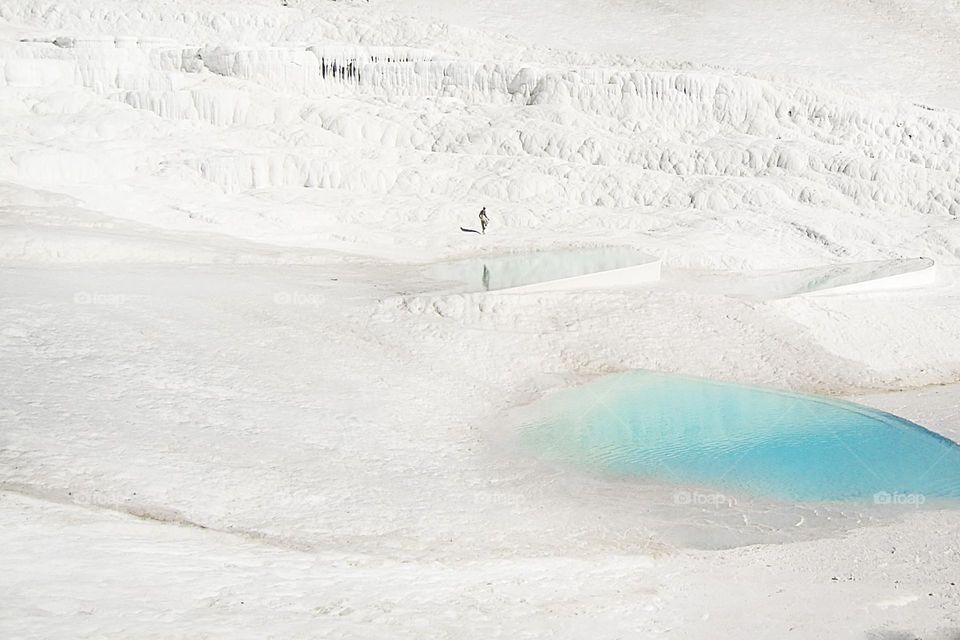 Tiny human walking by the white chalk mountain with blue lagoon 