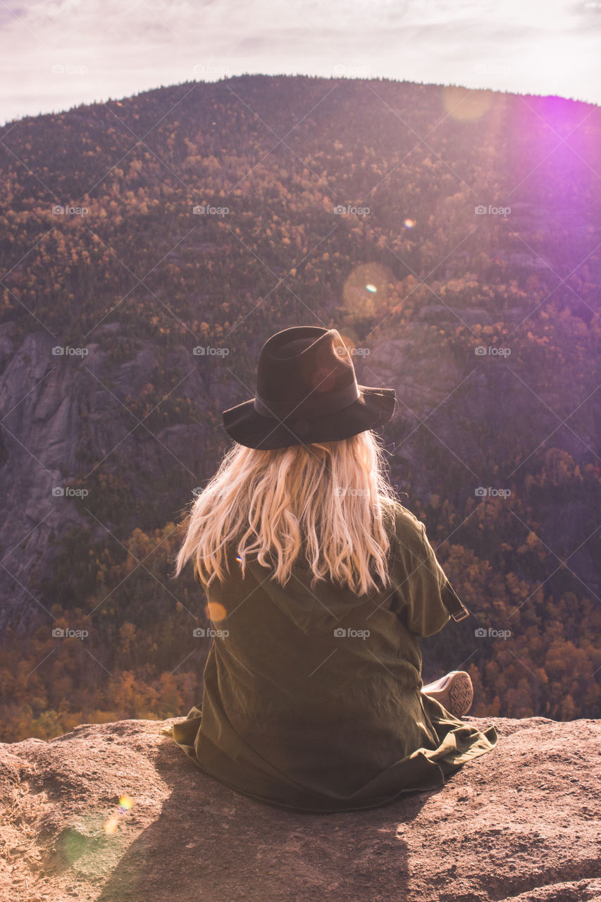 A young woman hiker looks out at the mountain range of a forest upstate New York in the Catskills mountains 