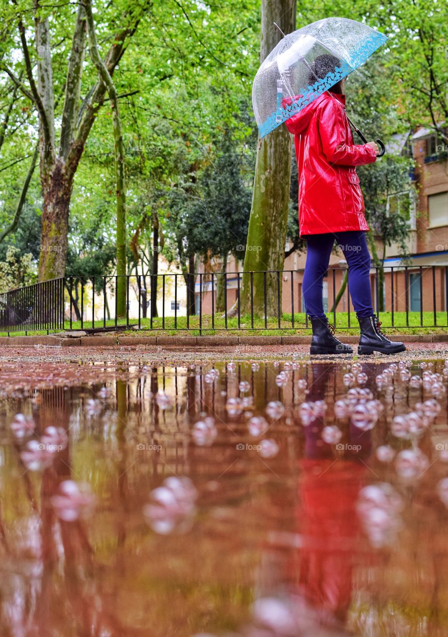 Young girl walking by the park on a rainy day