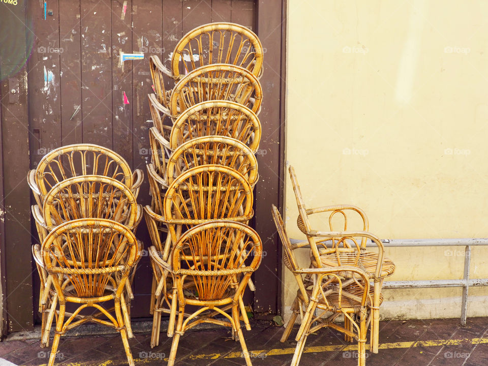 Cafe chairs piled up against yellow and brown wall on the Cours Saleya in Nice, France.