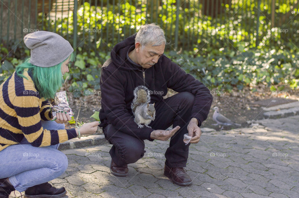 Feeding a squirrel girl with green hair alternative girl old man in the park