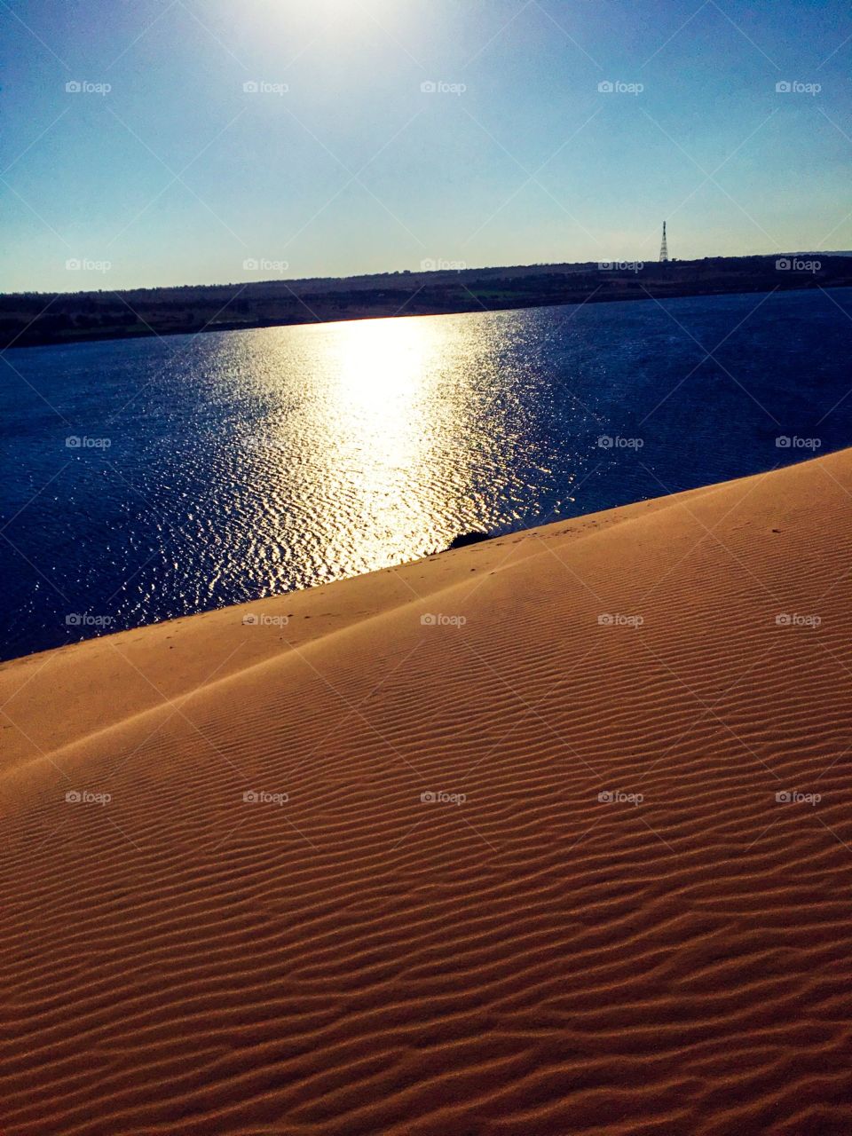 I standing on a sand dune  looking down below the lake, the afternoon light reflected in the water looks so beautiful