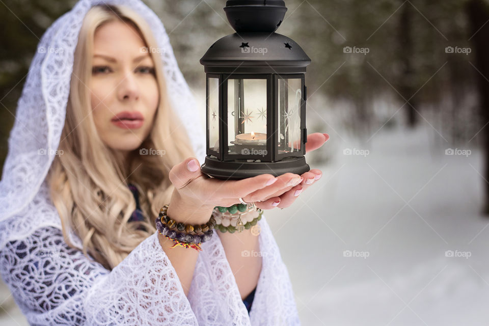 Woman wearing white robe holding ornate lamp