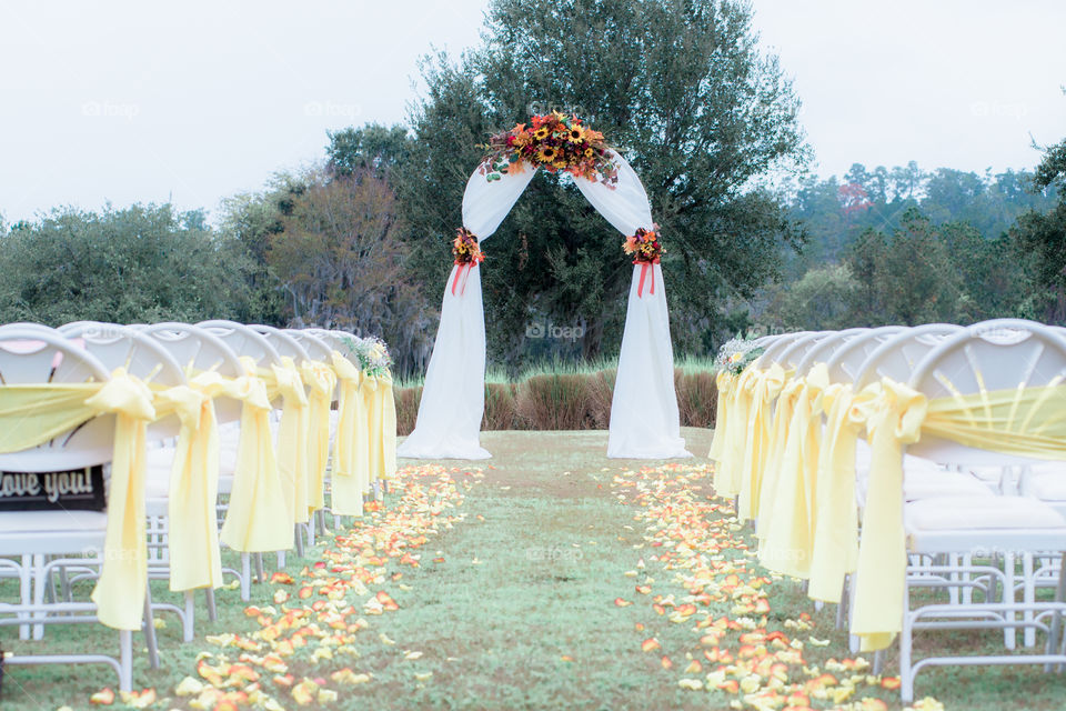 Wedding Ceremony Decor white chairs and yellow bows and ribbons