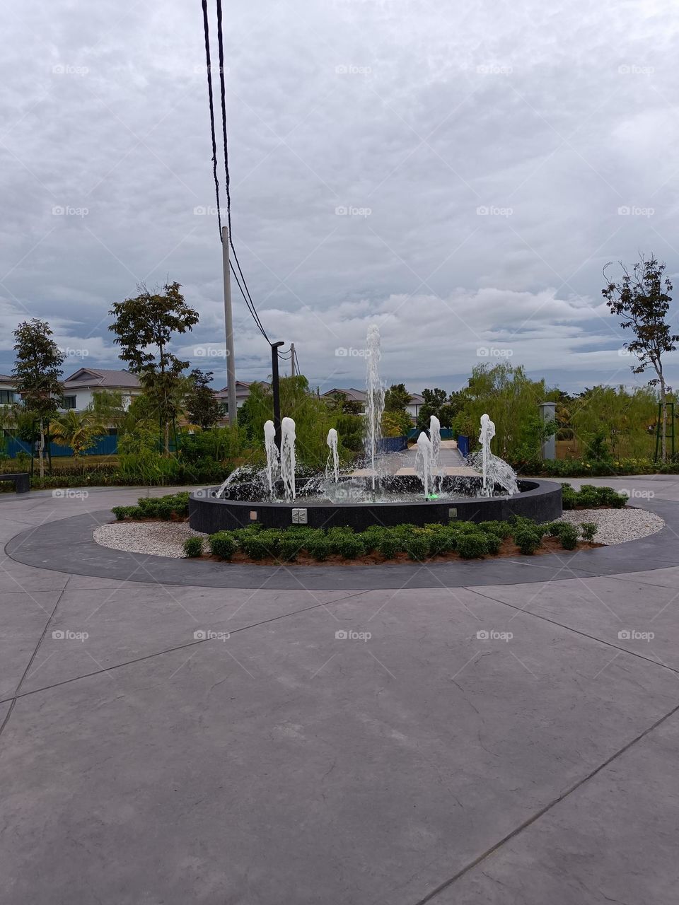 Beautiful landscape with clouded sky, fountaind and plants.A park scenery decorated with beautiful fountains.