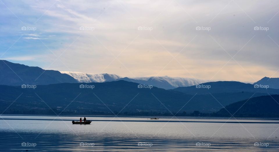 fishing in winter below the snowing mountains in greece