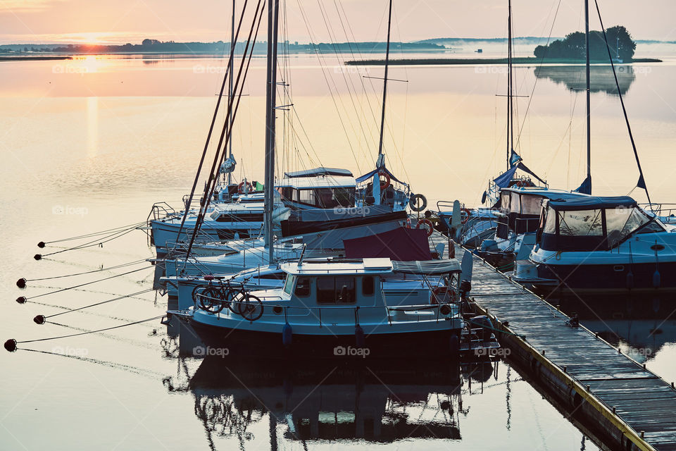 Yachts and boats moored in a harbour at sunrise. Candid people, real moments, authentic situations