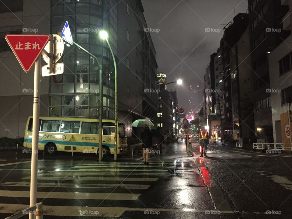 A wet street in tokio at night. Traffic lights are reflecting in the street. Roadworks ahead.