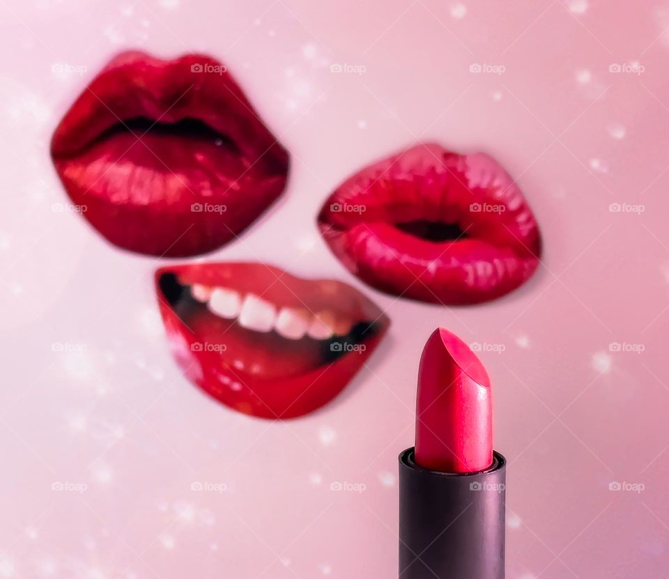 Lipstick in front of cut outs of lips against a pink background with a little added sparkle